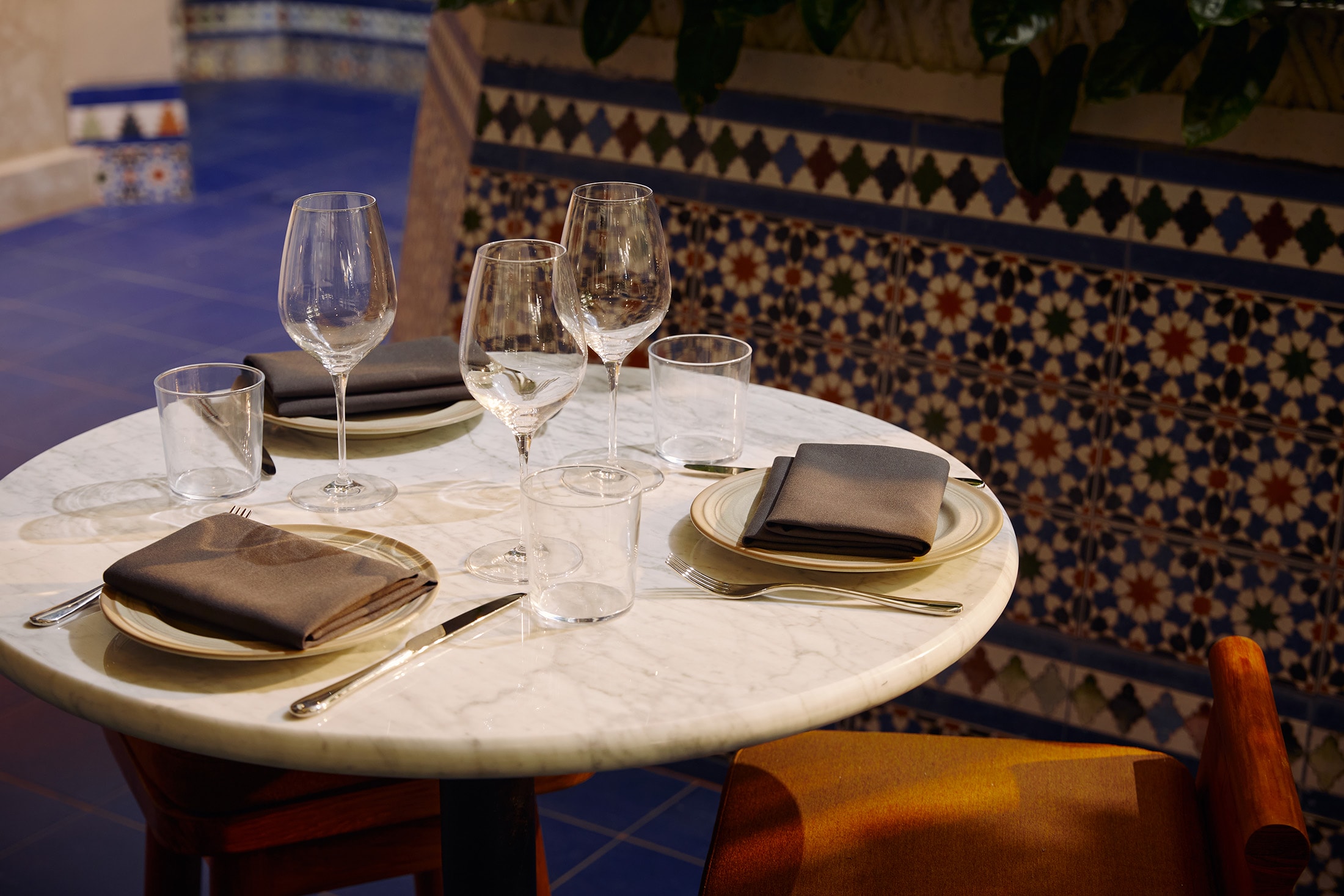 a round dining table set with wine glasses and plates