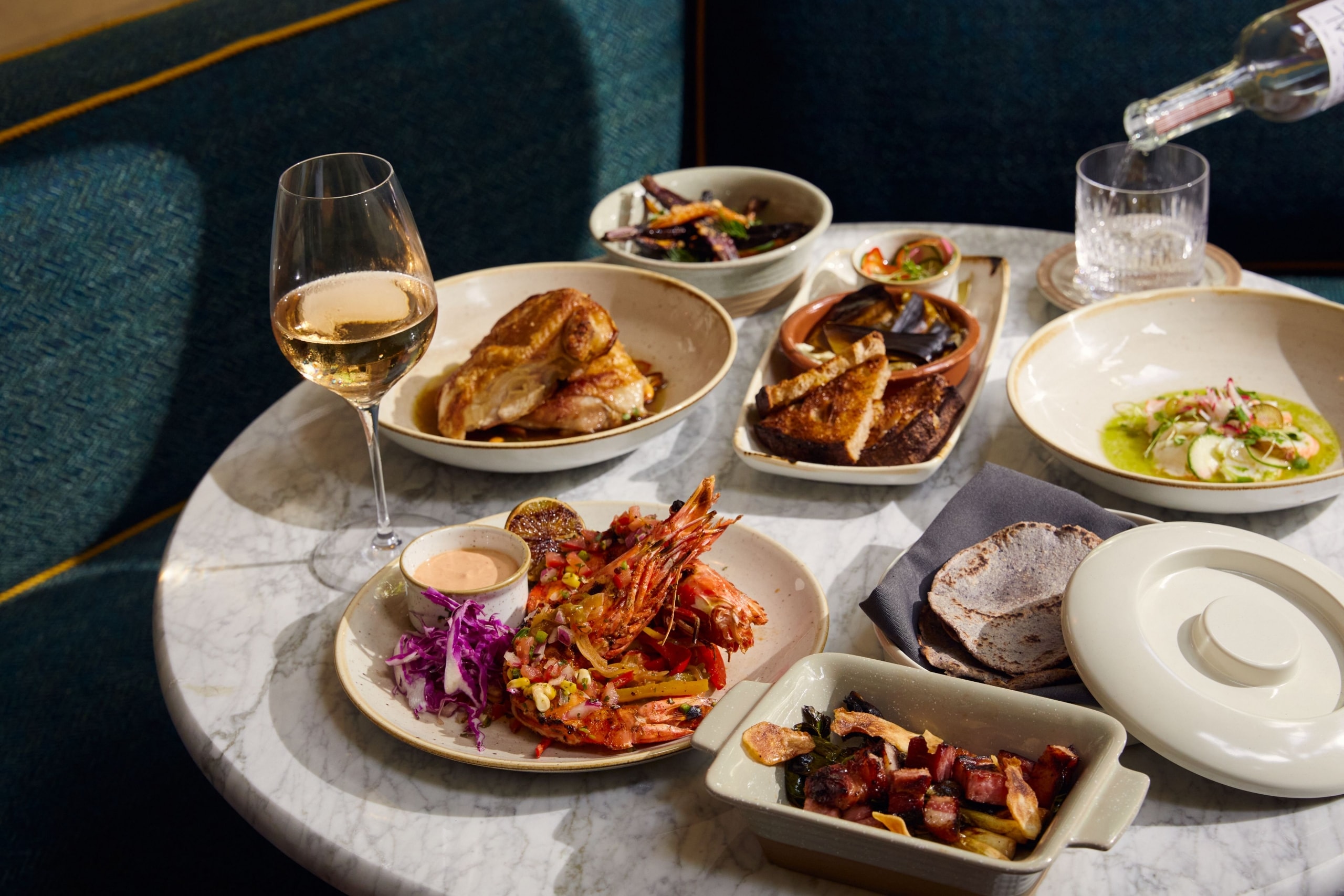 A table set with various dishes and glasses of wine.