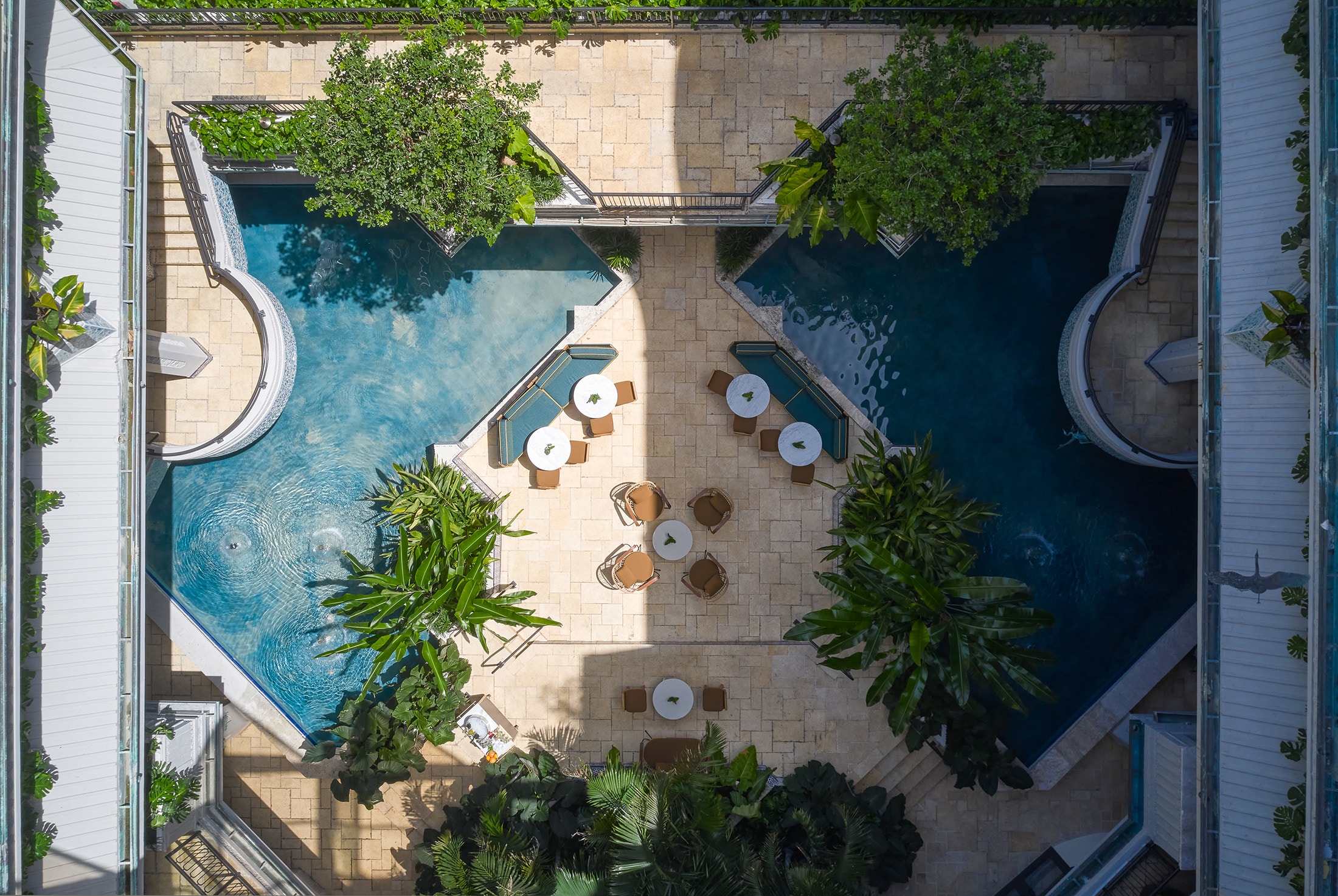 An aerial view of a pool area with a pool, furniture, and plants.
