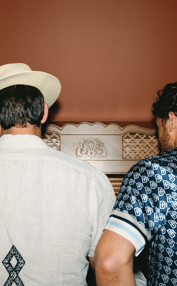 two people playing the piano from behind