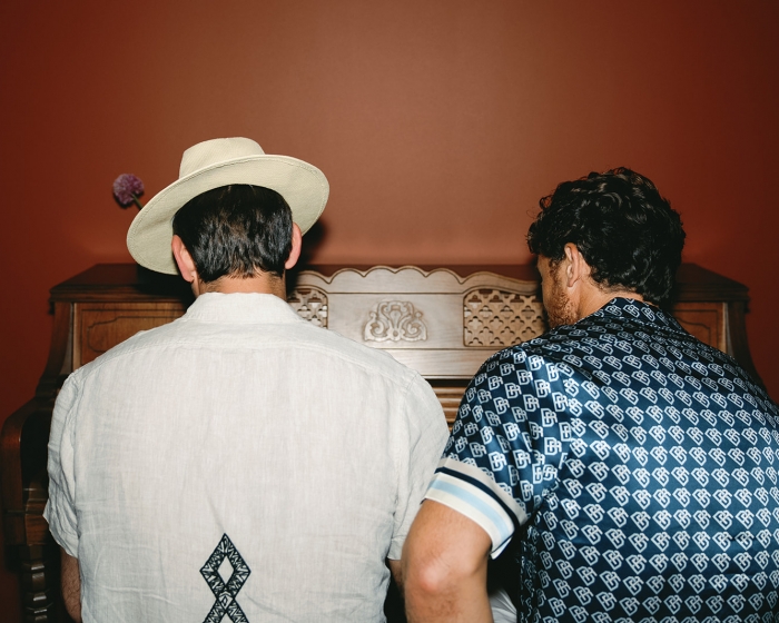 two people playing the piano from behind