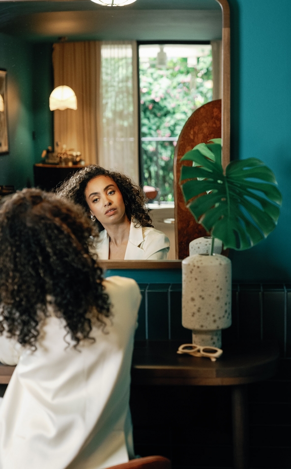 a woman doing her hair in the mirror
