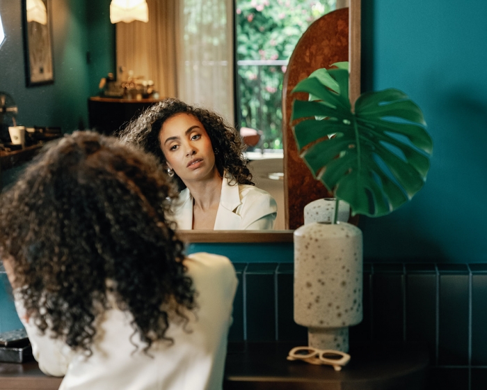 a woman doing her hair in the mirror