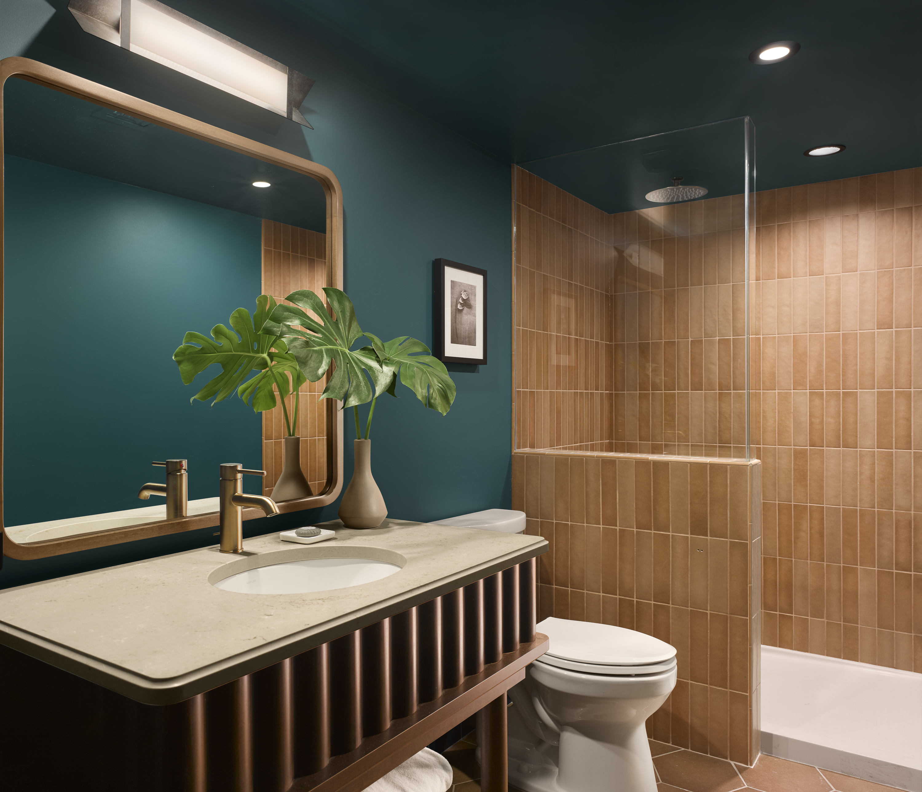 A modern bathroom with teal walls, wood tile, and gold fixtures.