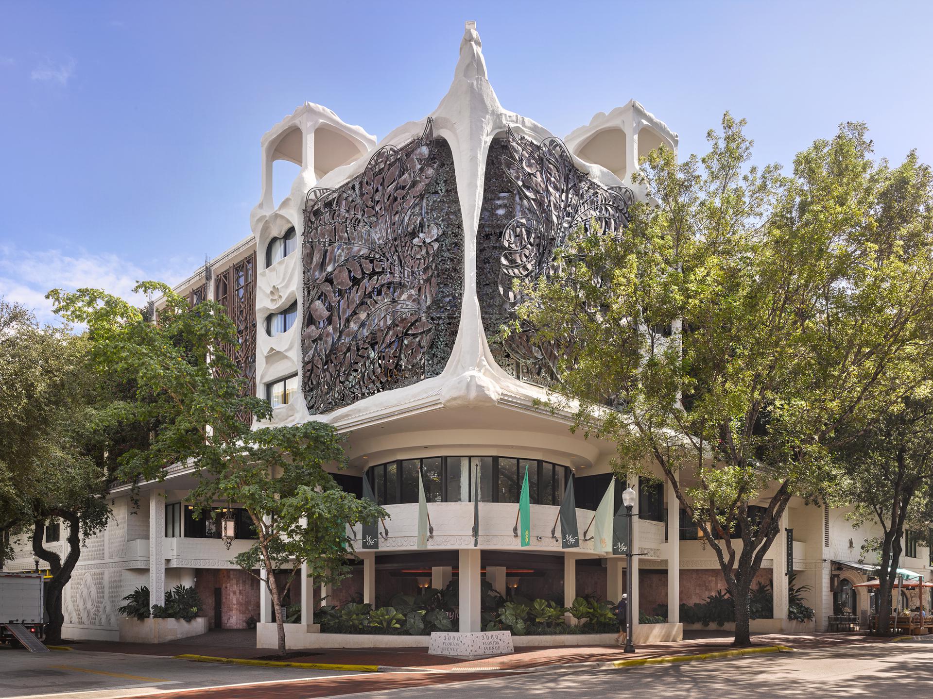 A white building with a unique design and trees in front of it.